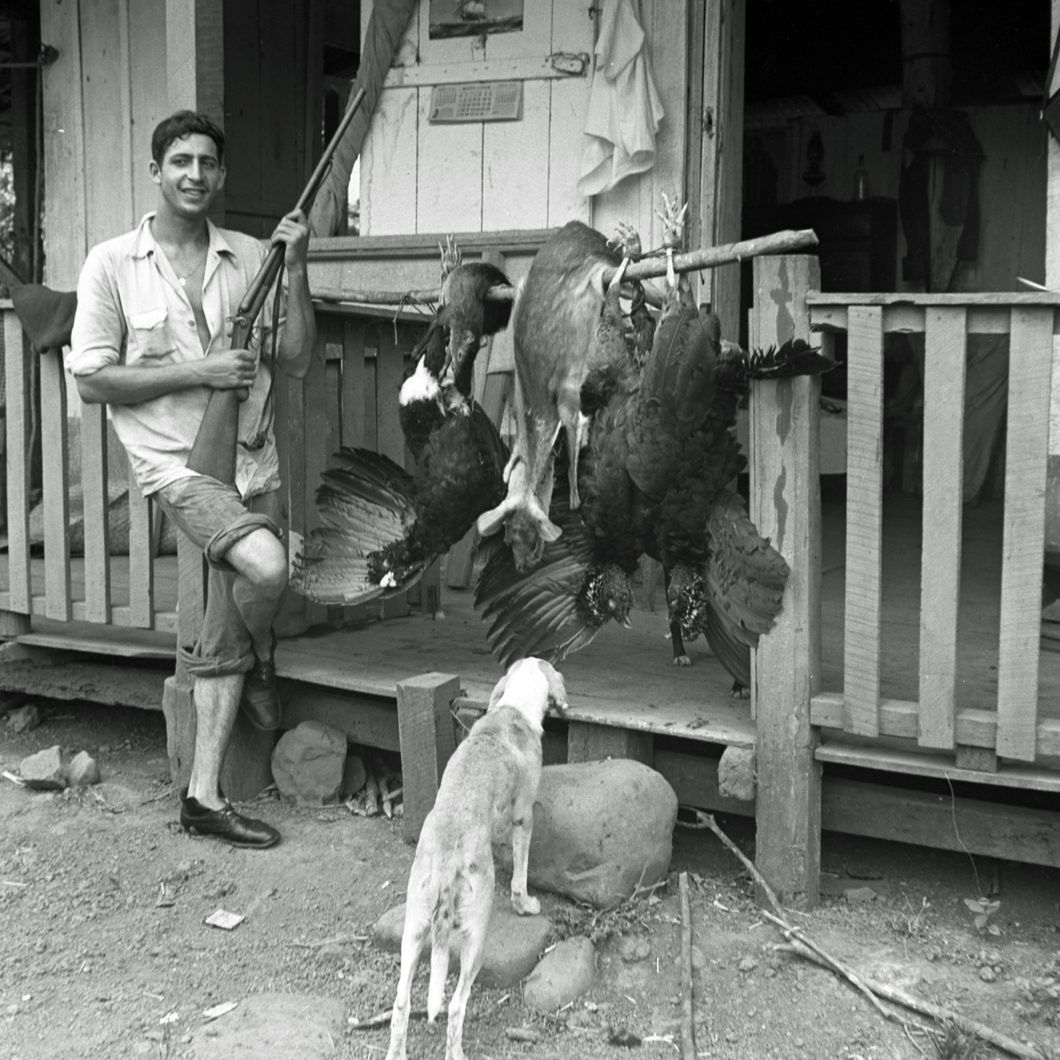 Man posing in front of cabin with dog